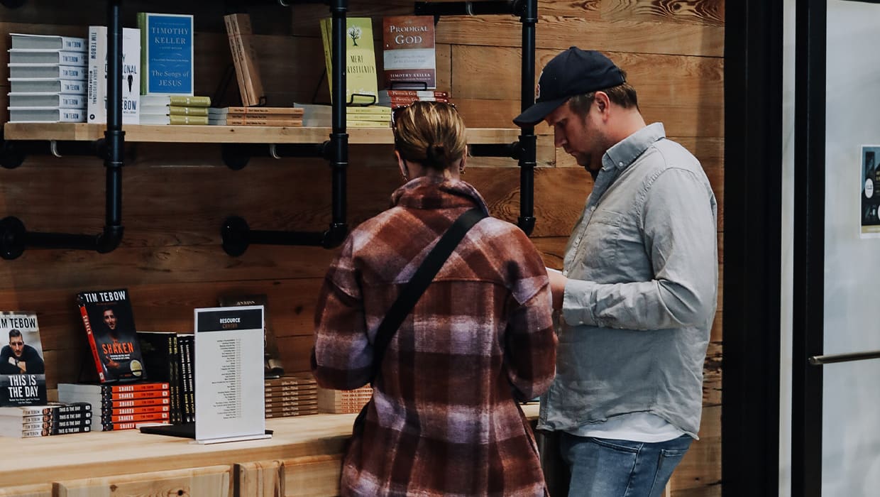 Two people browsing the resource center shelves at an Eleven22 campus