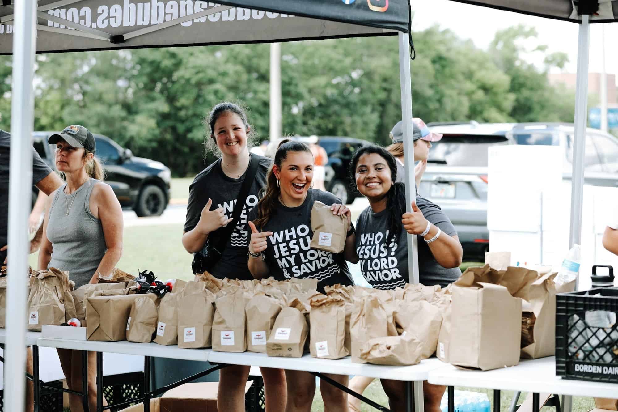 Volunteers laughing while handing out lunches at Beach Baptism